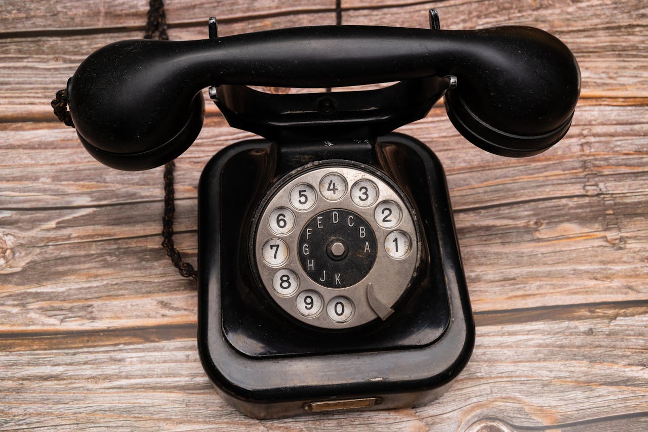 Classic black rotary telephone with dial on wooden background, evoking nostalgia.